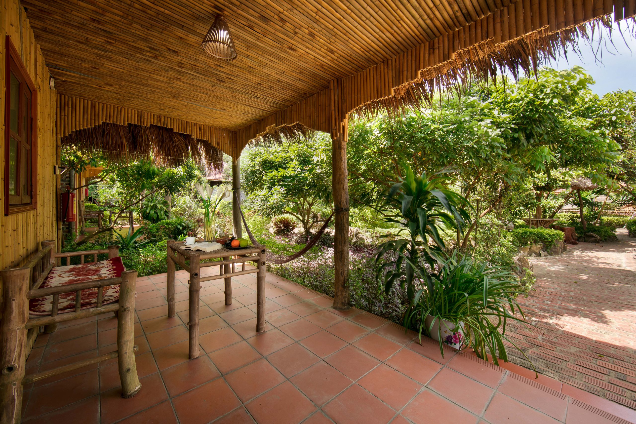 Covered wooden veranda with tables looking onto a tropical garden at Lan Homestay, Viet Hai