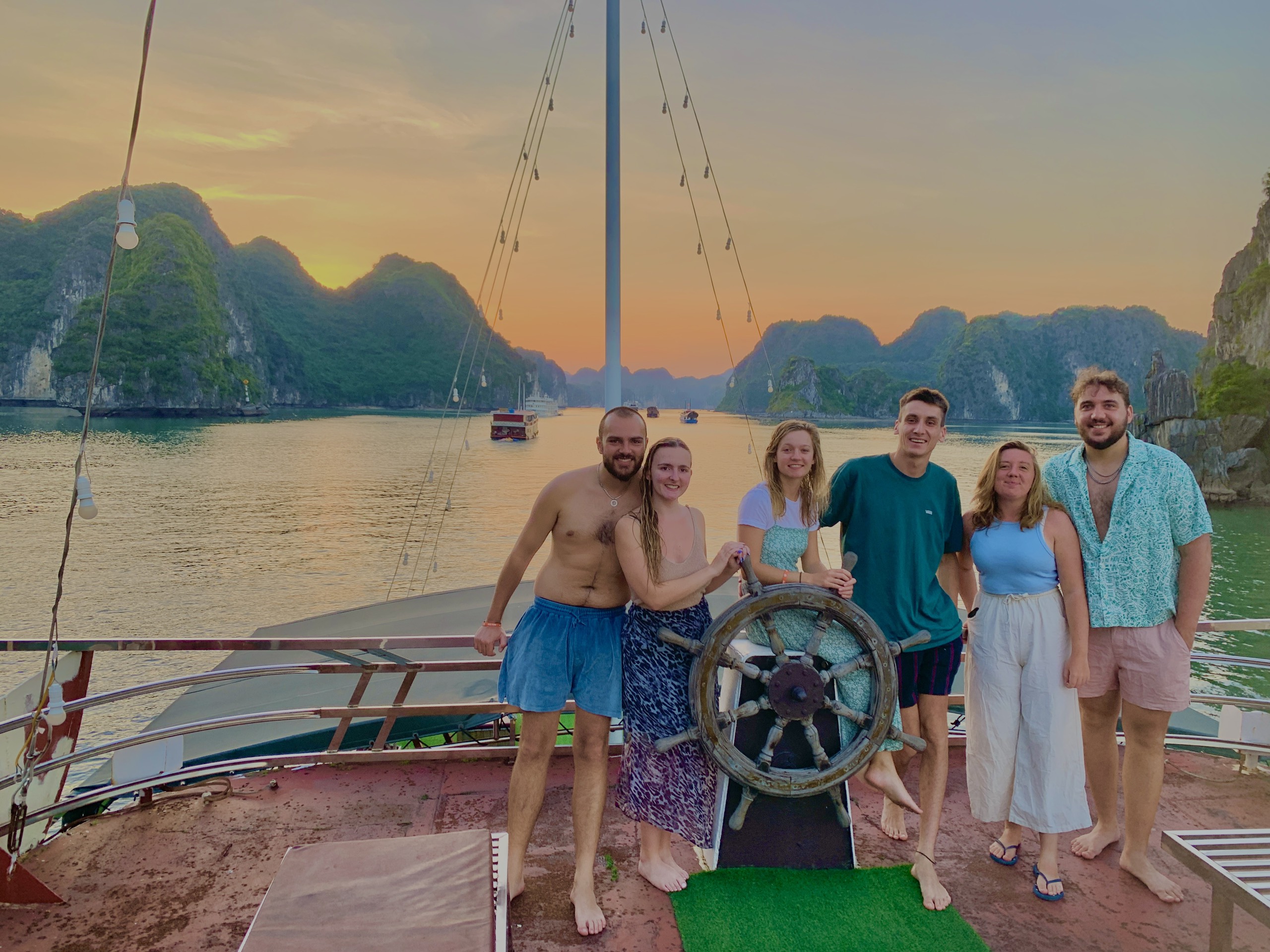 Group of travellers standing on the deck of a boat in Lan Ha Bay at sunset