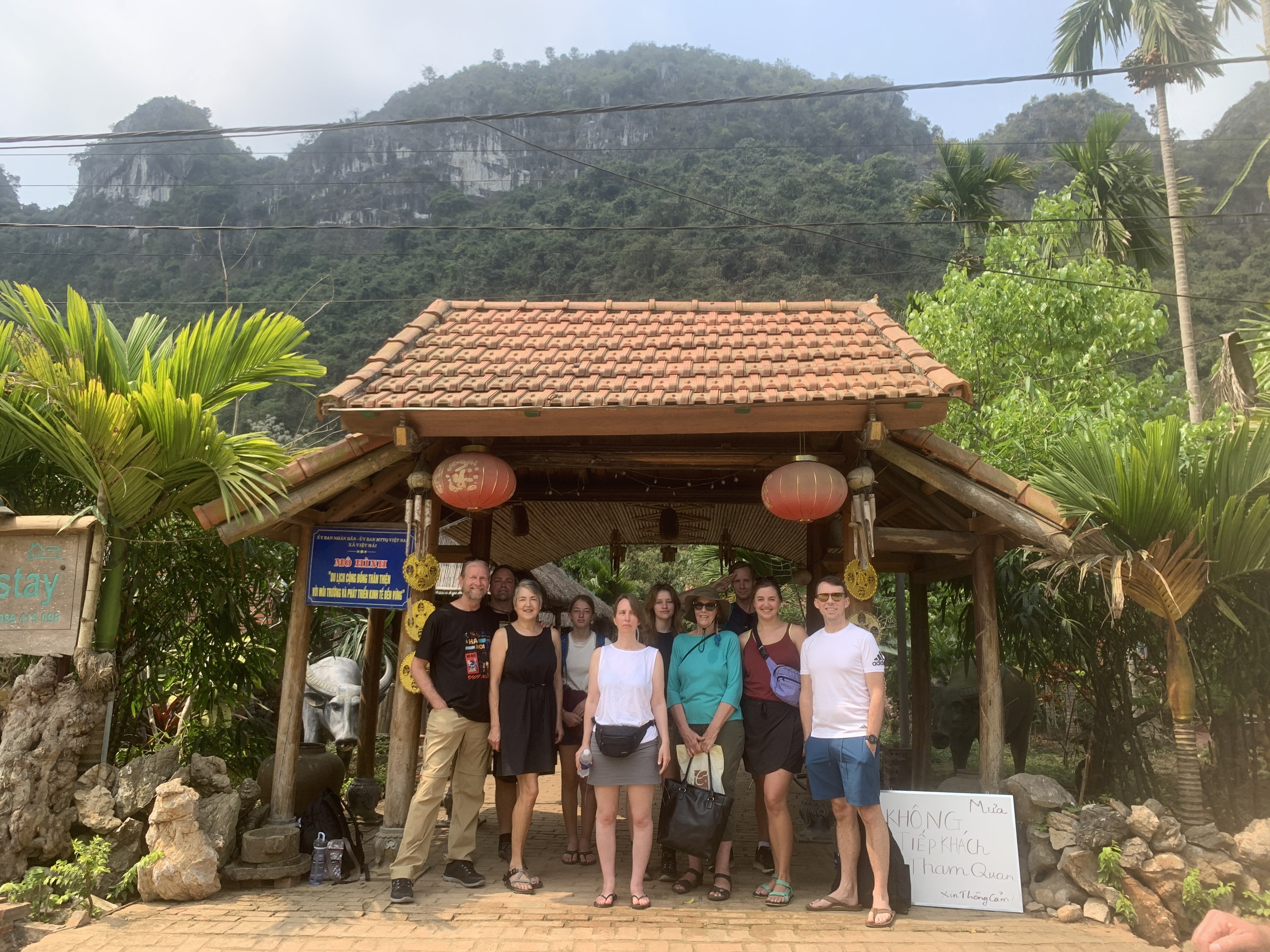 Guests gathered under a traditional wooden pavilion at a village homestay in Cat Ba
