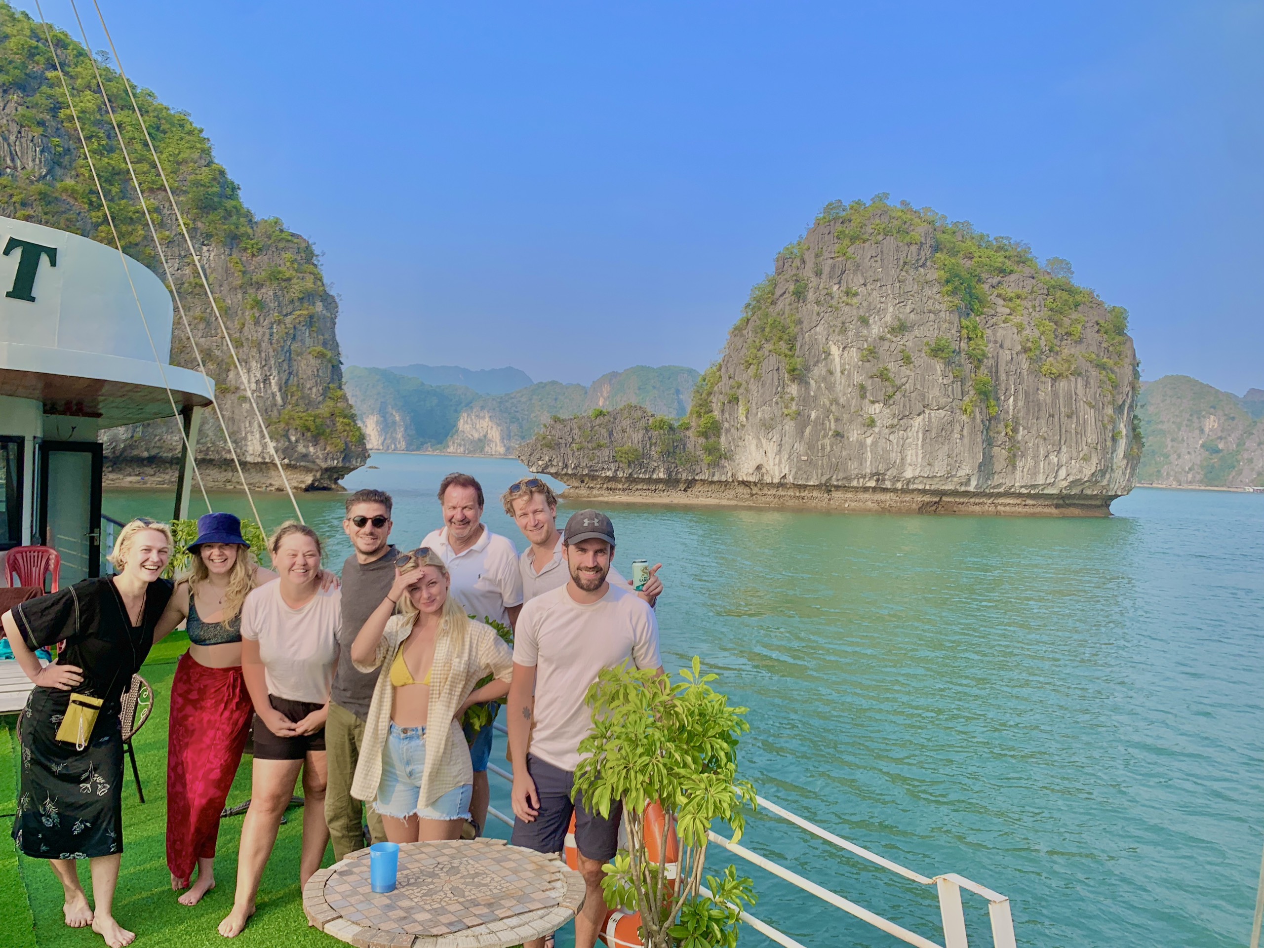 Group of travellers on a day boat with limestone karsts behind them in Lan Ha Bay