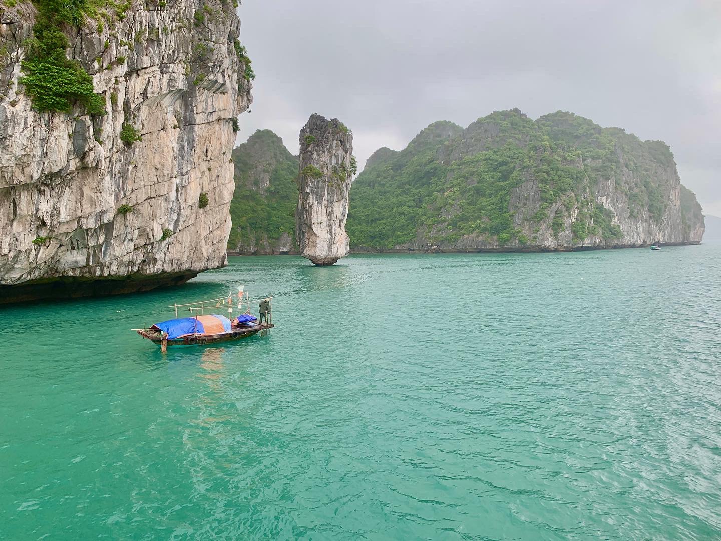 Small wooden fishing boat between limestone karsts on the way to Viet Hai Village, Lan Ha Bay