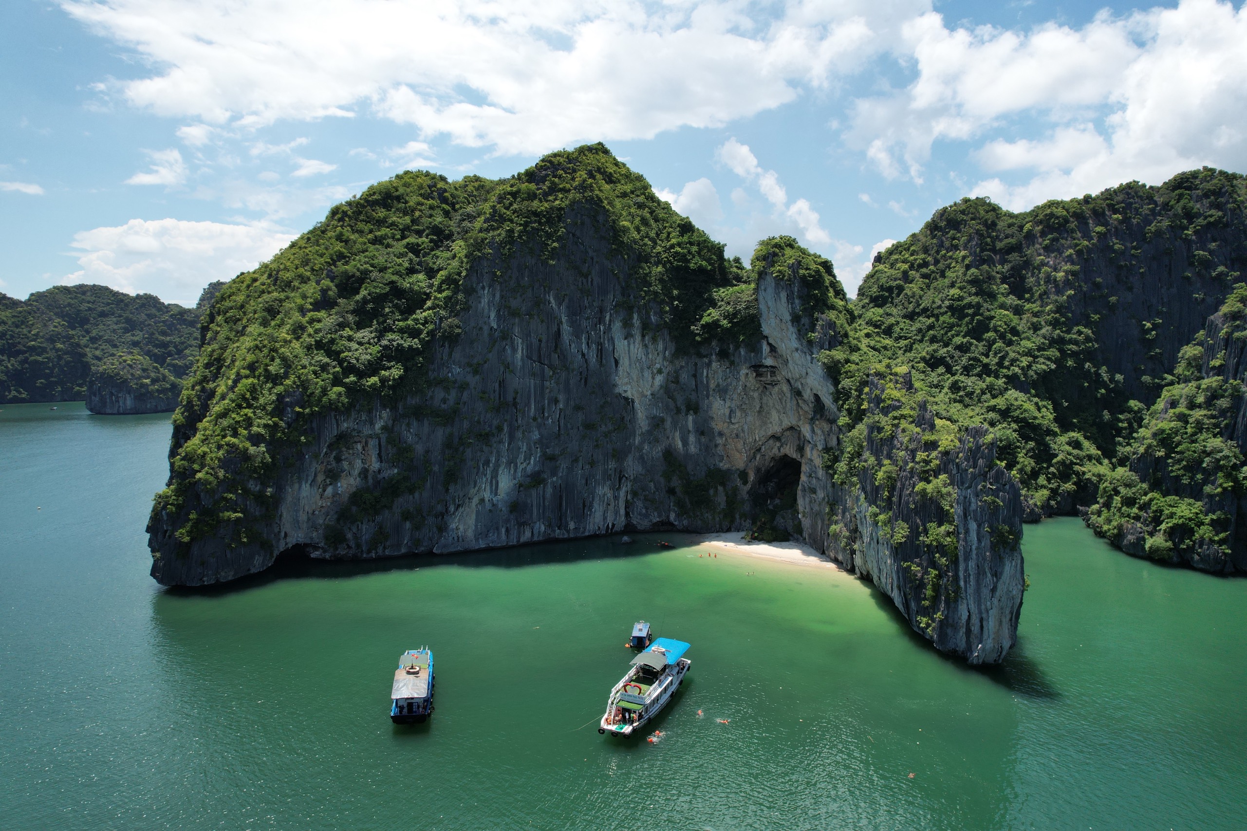Turquoise water and limestone karsts in Lan Ha Bay with a small boat on a bright summer day