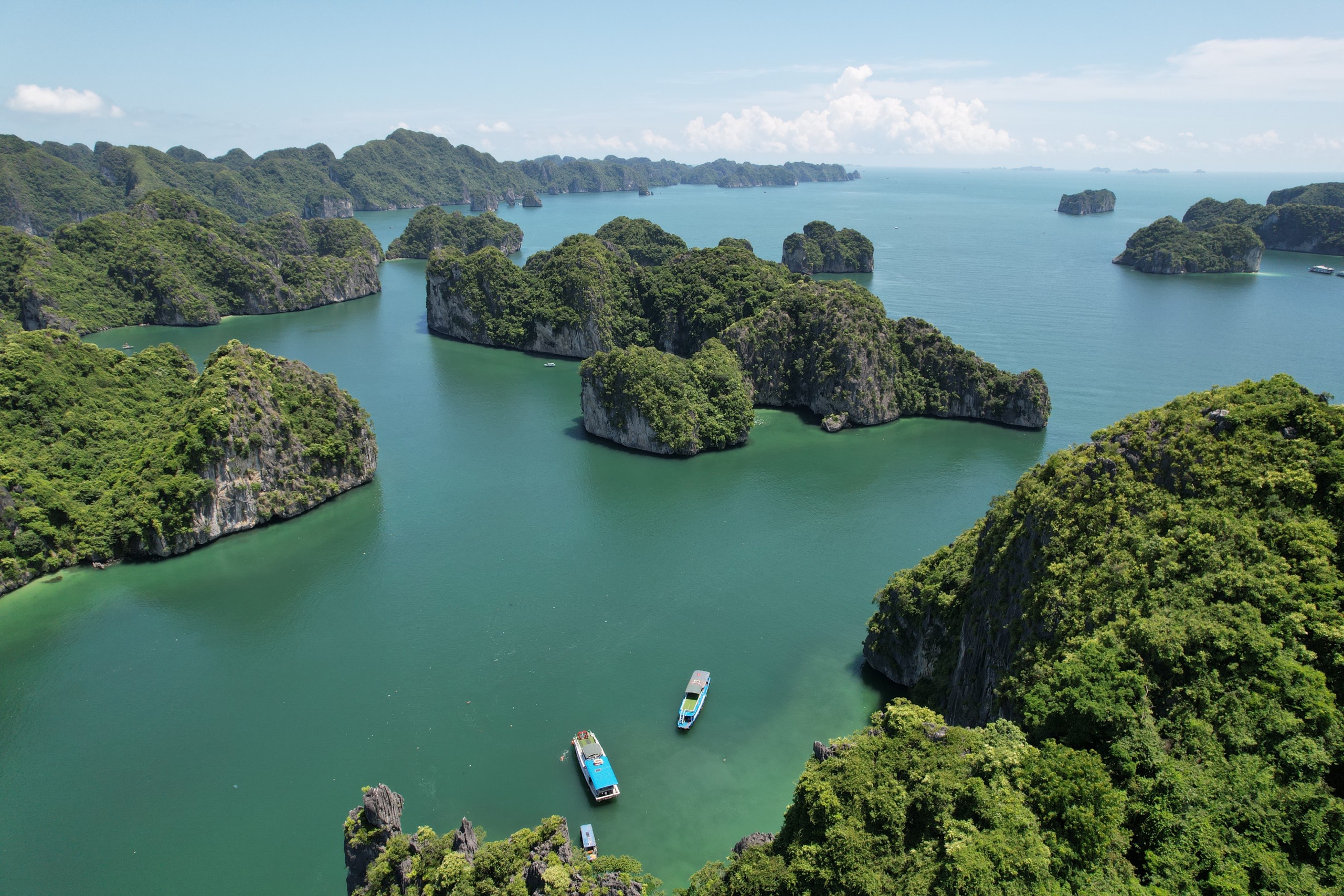 Aerial view of calm bay with boats and forested karst islands near Cat Ba