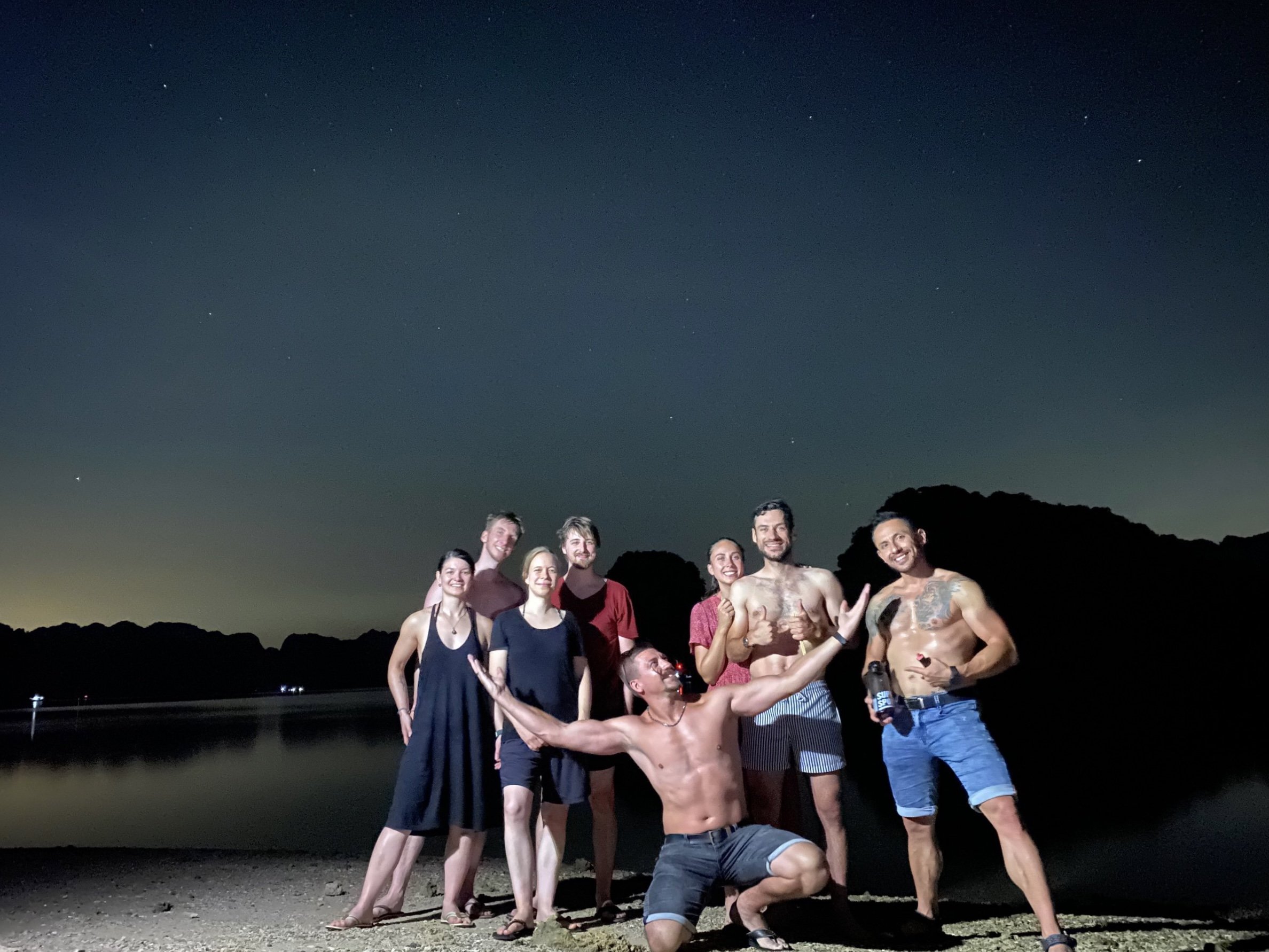 Group of travellers standing together under the night sky on Cat Ba Island