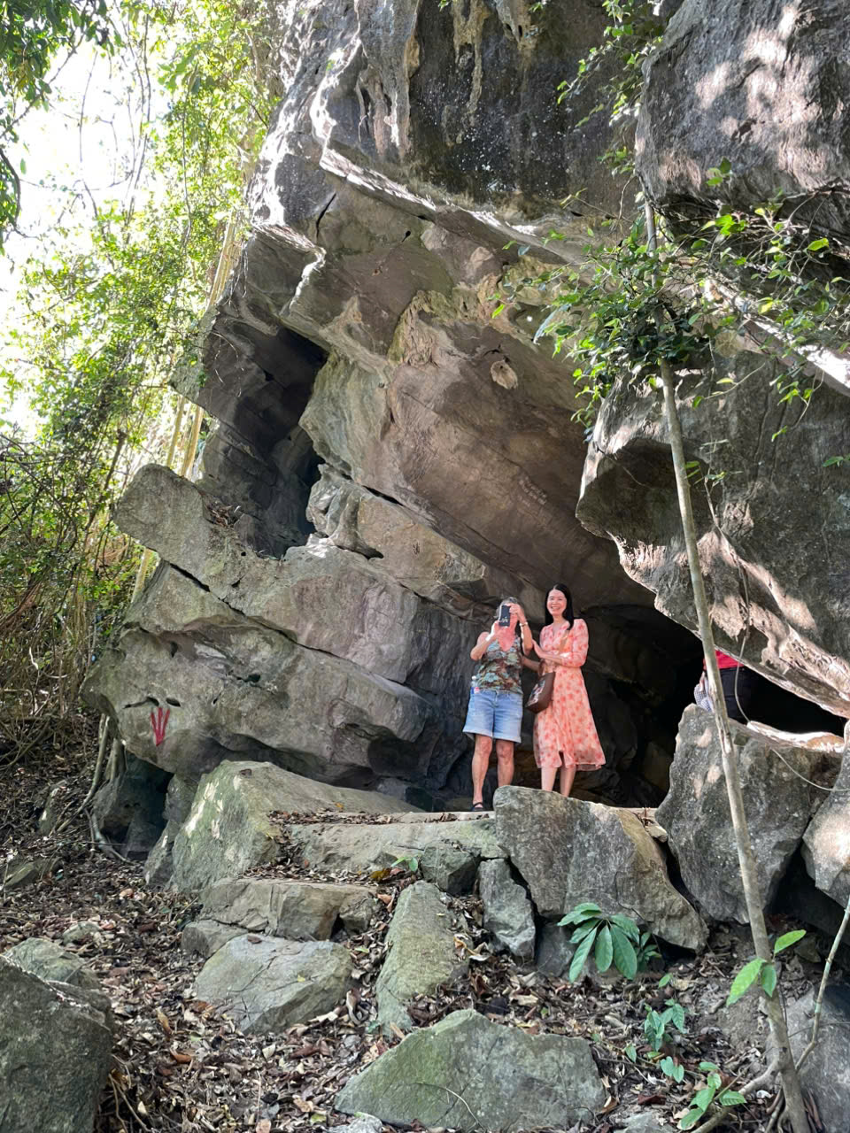 Hikers trekking through Cat Ba National Park jungle with massive limestone rock formations and tropical forest