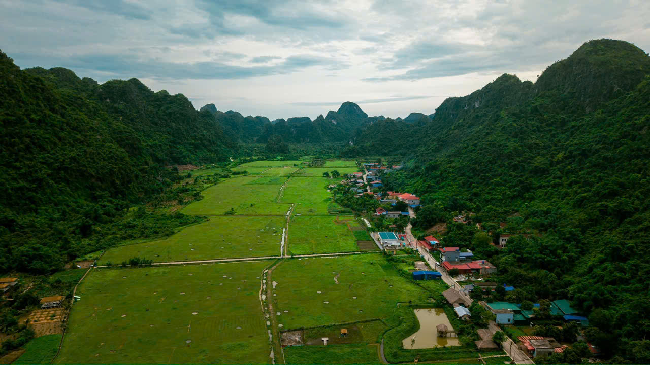 Aerial drone view of Viet Hai village and rice fields enclosed by limestone hills, Cat Ba National Park