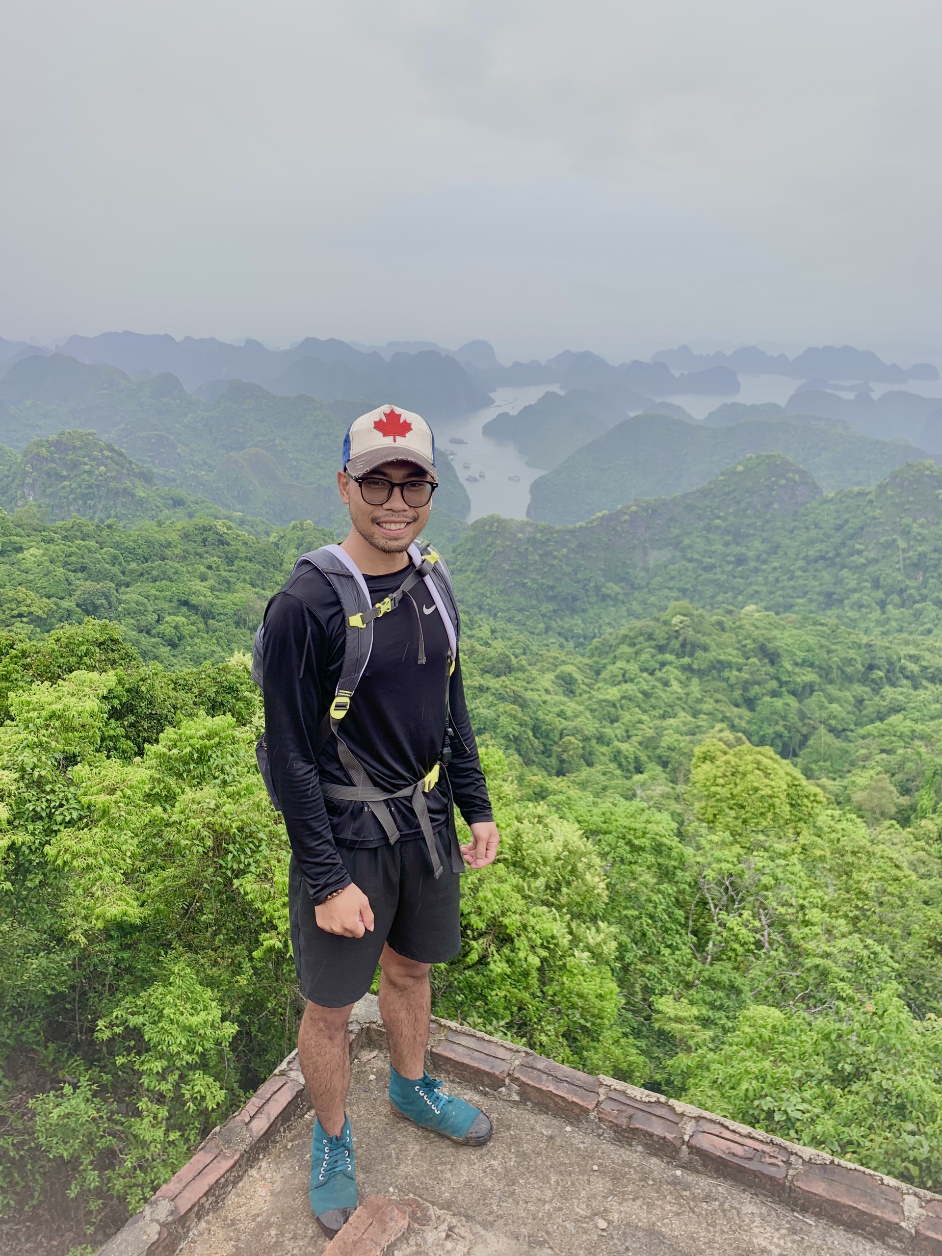 Hiker at Ngu Lam Peak viewpoint, Cat Ba National Park, with panoramic bay views