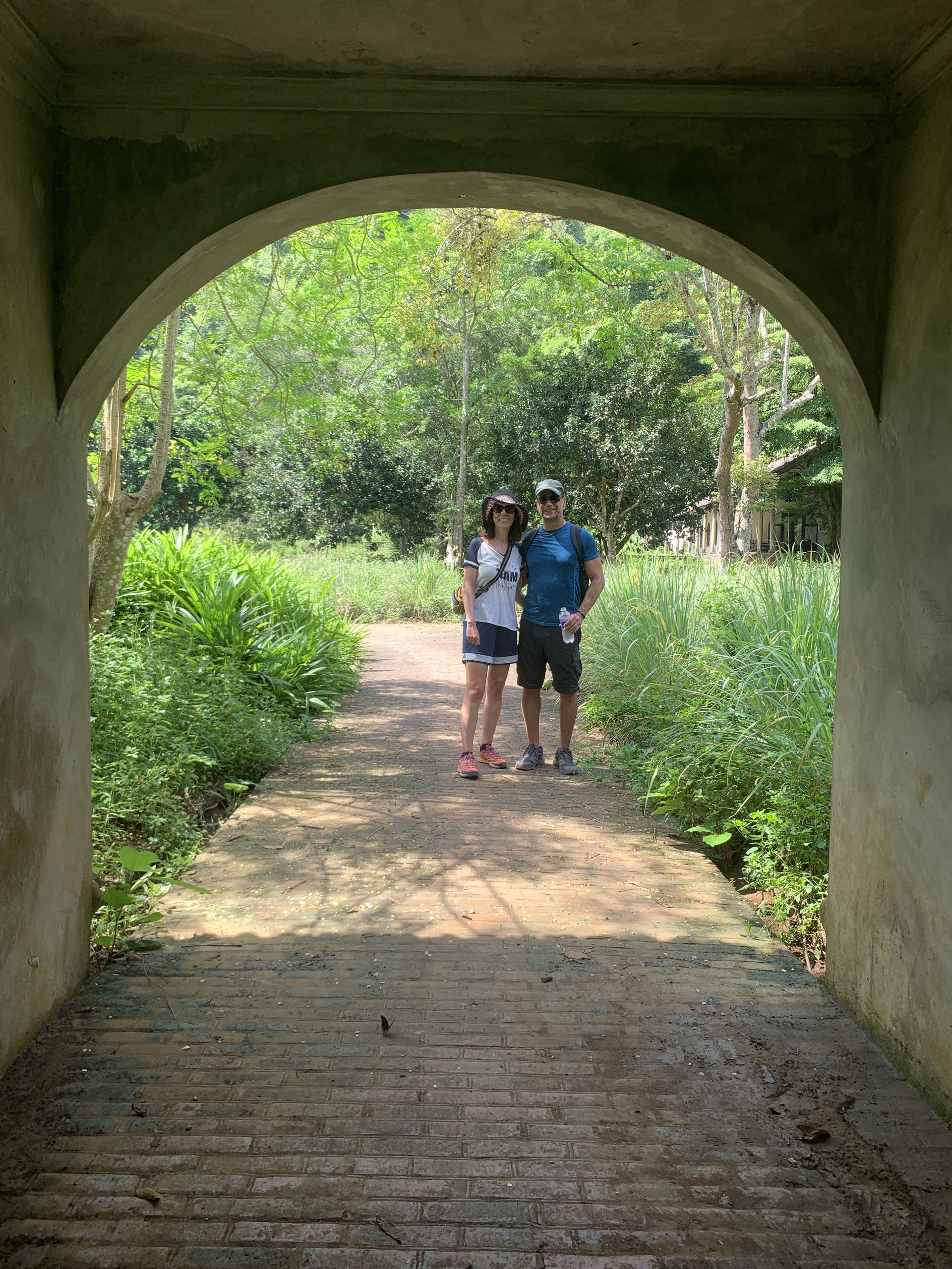 Couple walking through arched gateway into Viet Hai village, Cat Ba Island