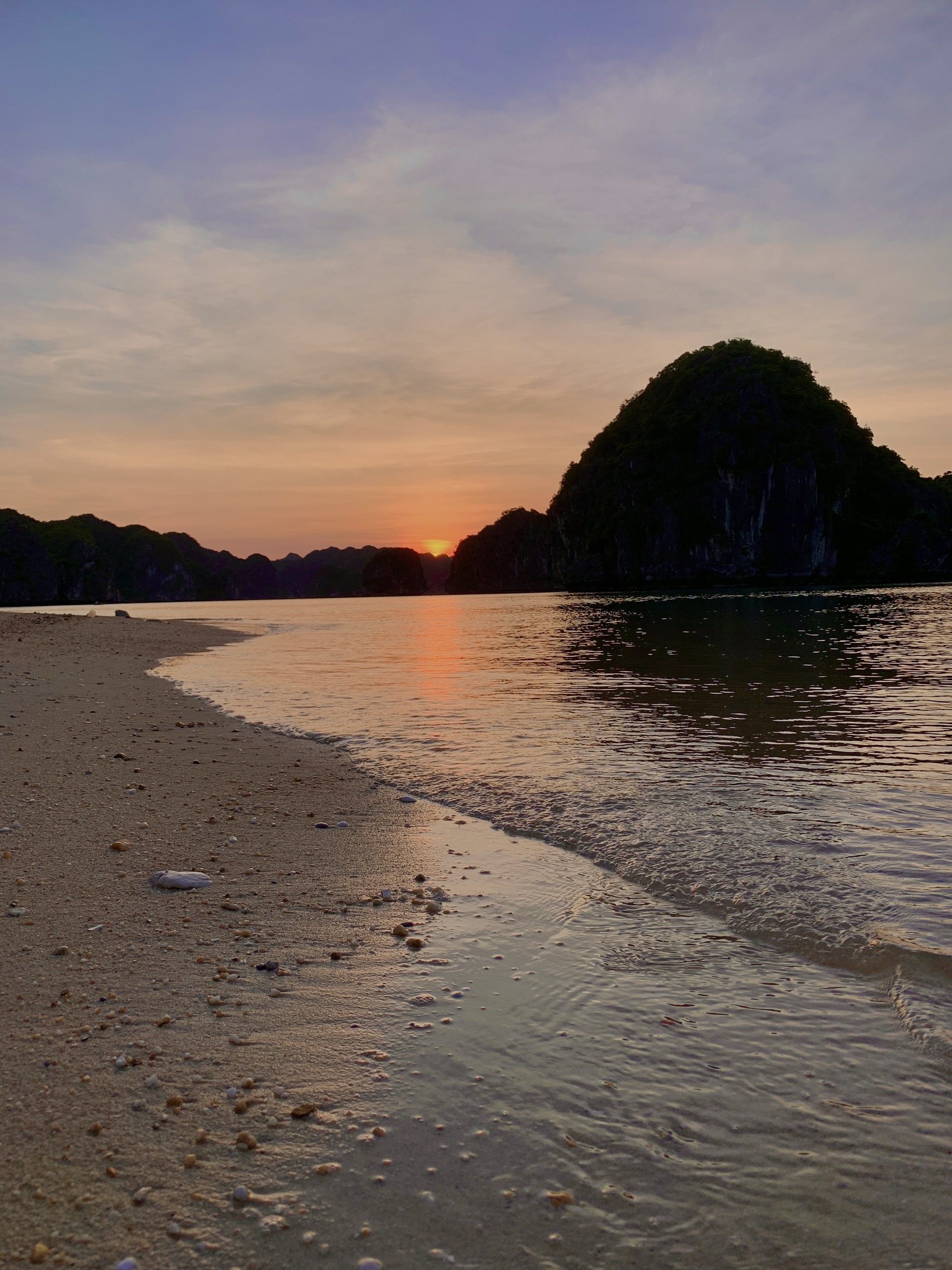 Kayaks resting on a hidden beach at sunset in Lan Ha Bay