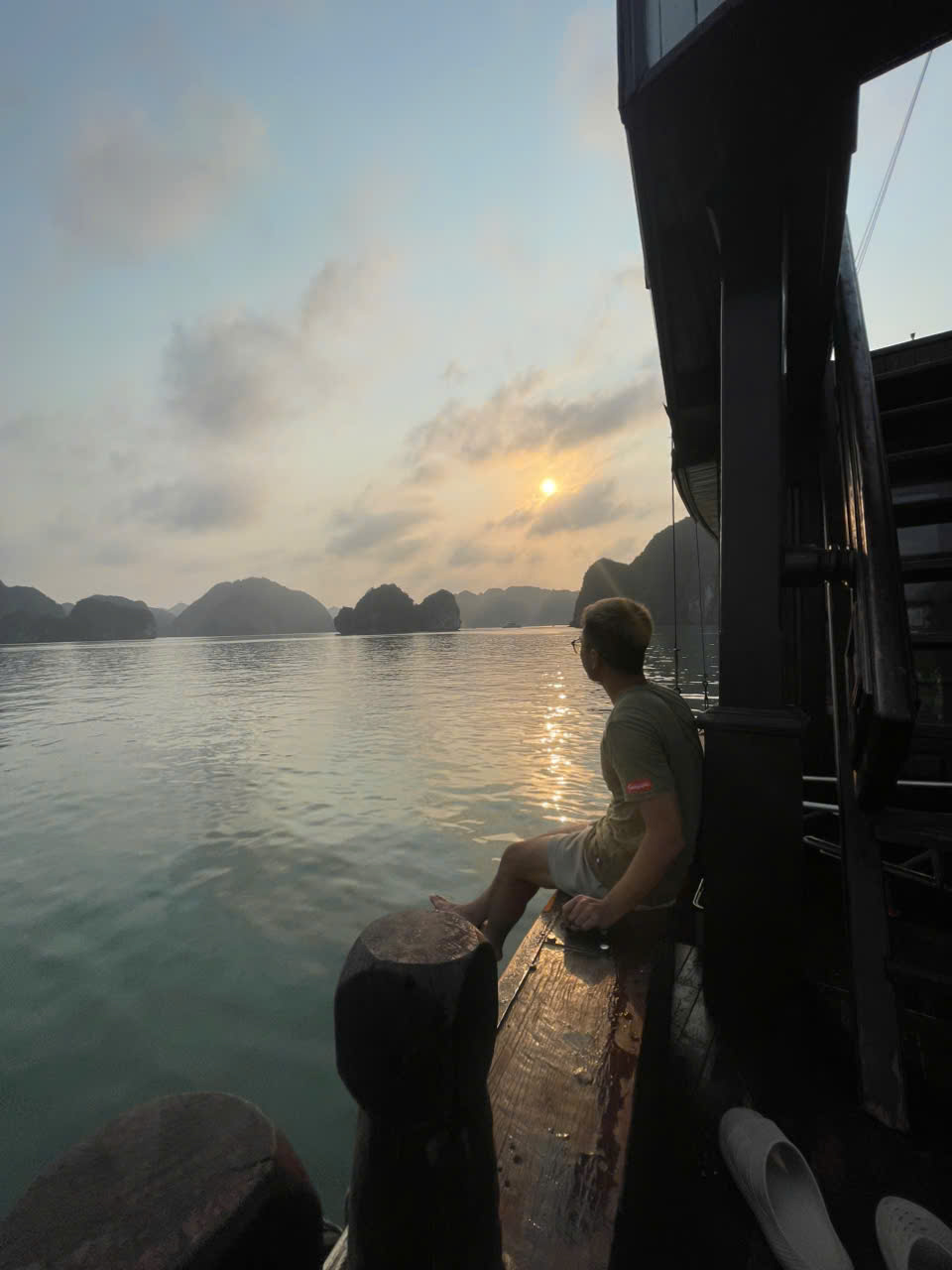 Guest relaxing on cruise boat bow at sunset over Lan Ha Bay