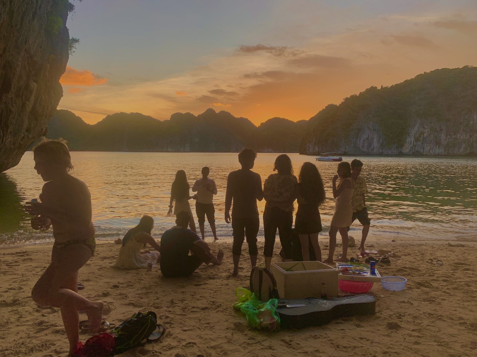 Group gathered on a beach at sunset in Lan Ha Bay