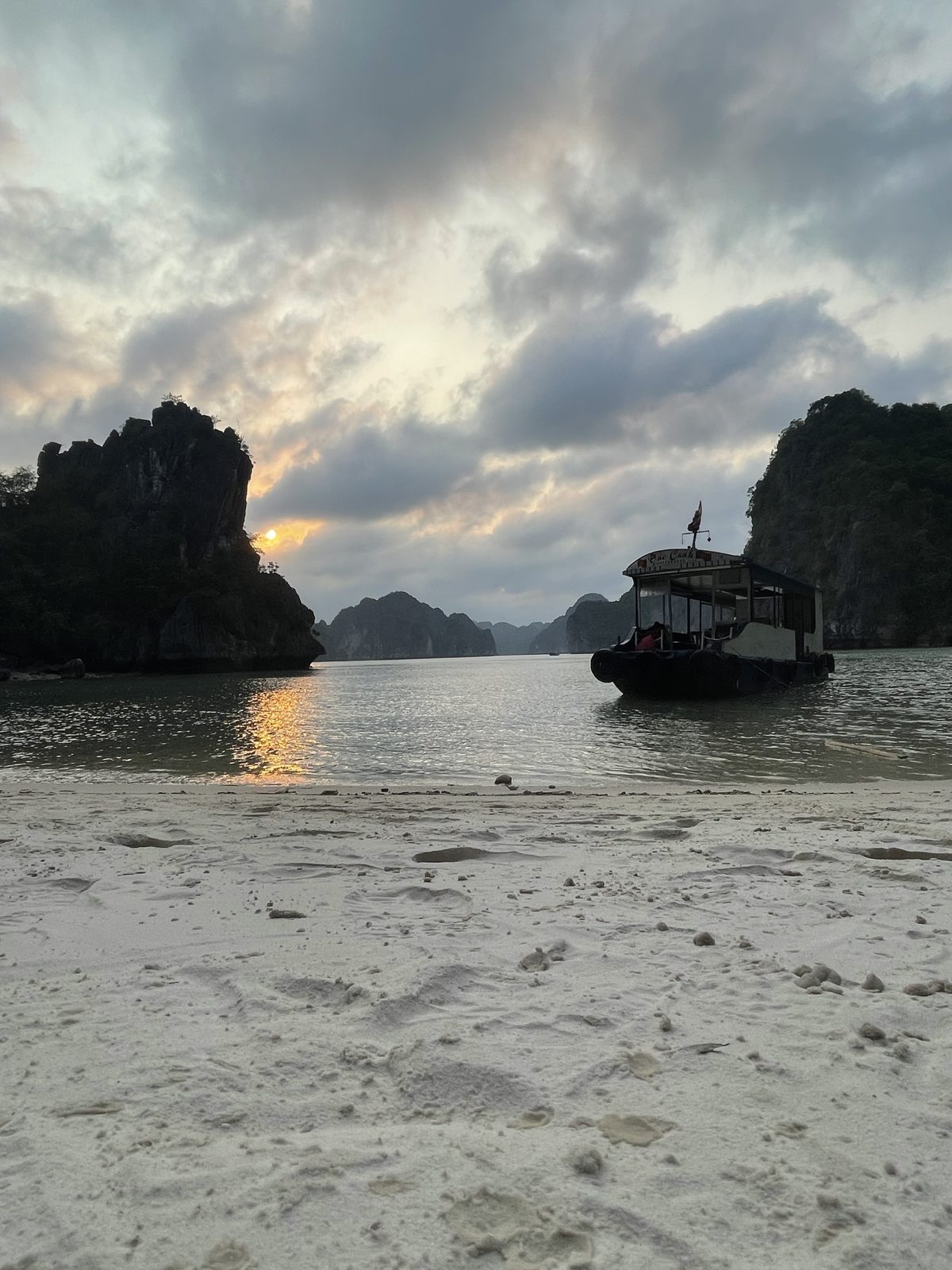 Wooden boat moored off a Lan Ha Bay beach at sunset, Cat Ba Island