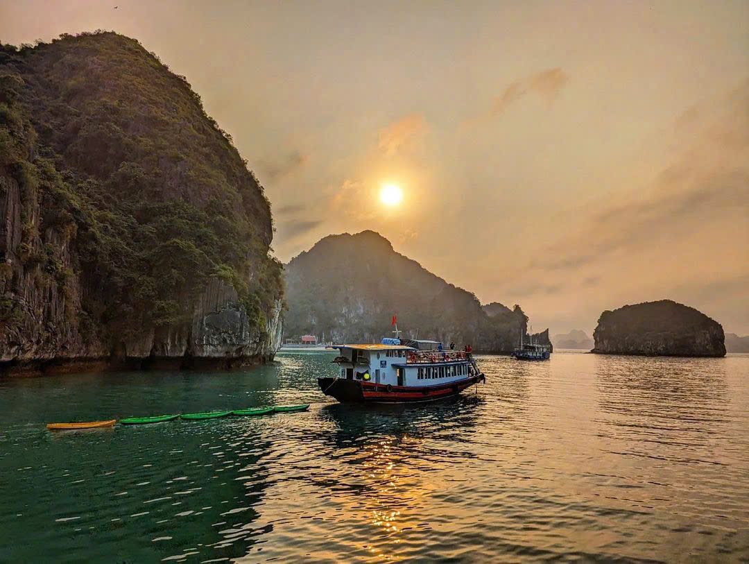 Boat silhouetted against the setting sun in Lan Ha Bay
