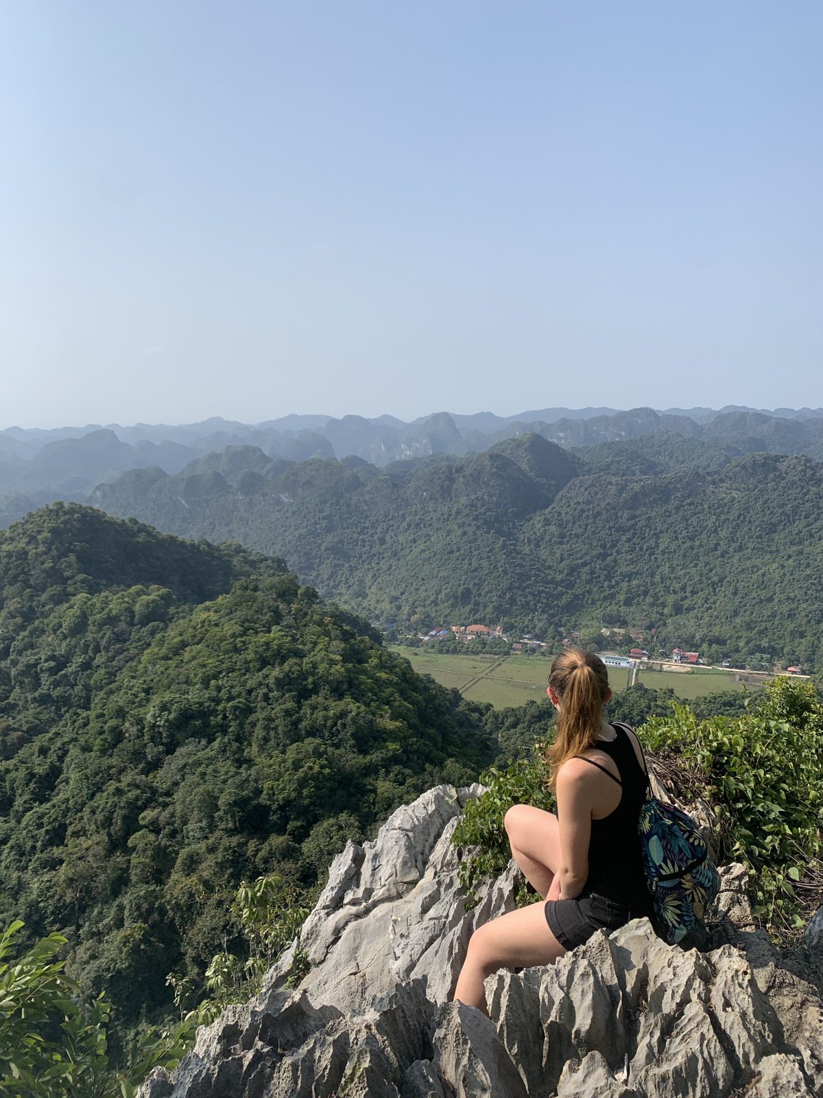 Woman resting on a limestone outcrop above the jungle in Cat Ba National Park