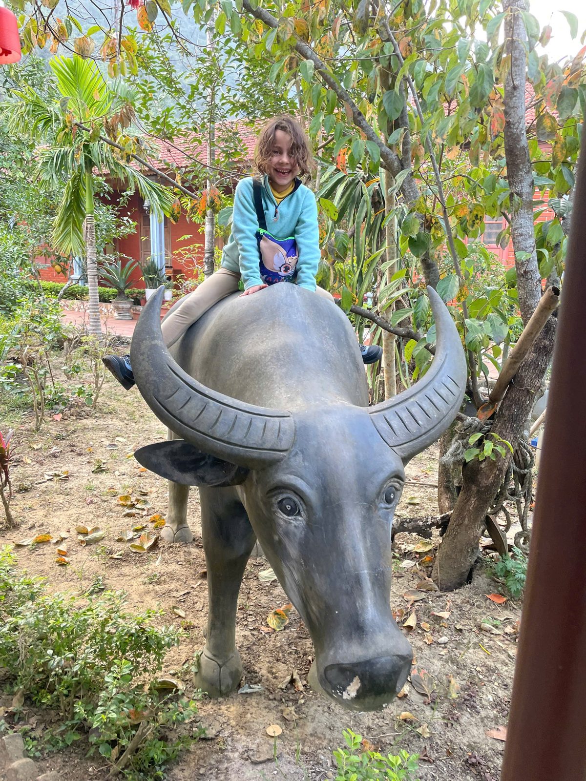 Child sitting on a buffalo statue in Viet Hai Village, Cat Ba Island