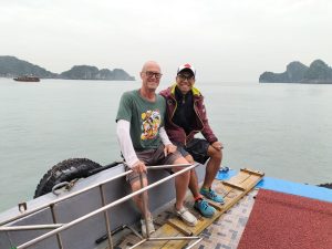 Couple sitting on the bow of a boat crossing Lan Ha Bay