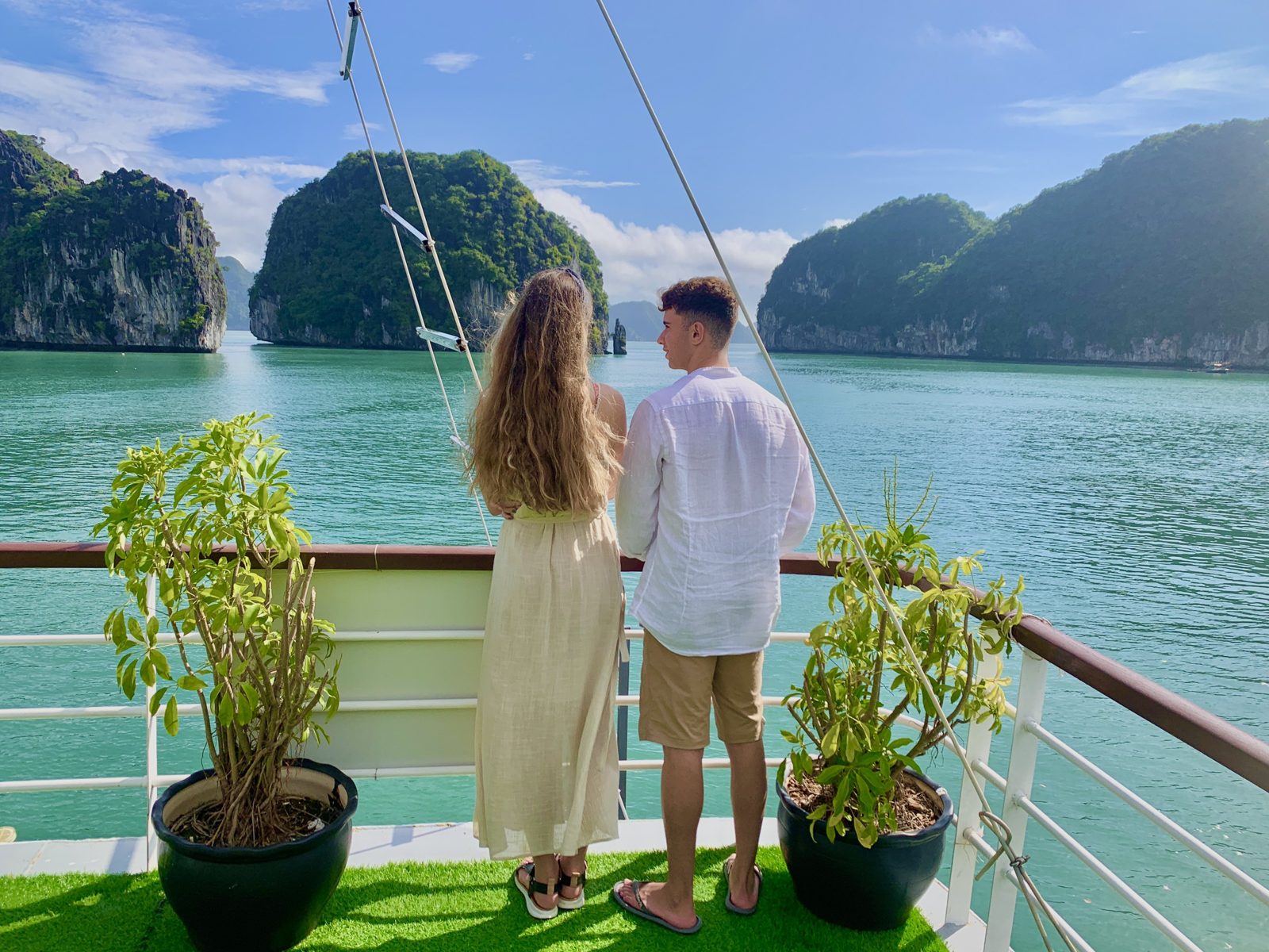 Couple standing on the deck of a boat looking out over Lan Ha Bay