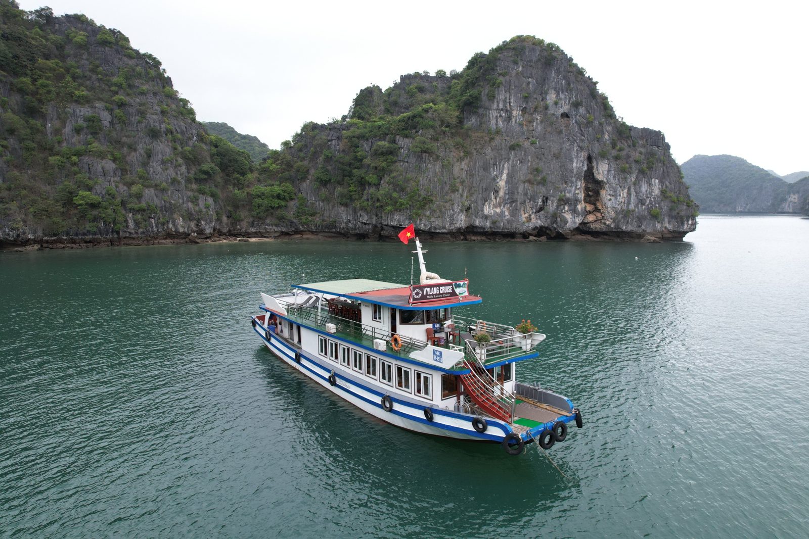 Day boat anchored beside a limestone karst in Lan Ha Bay