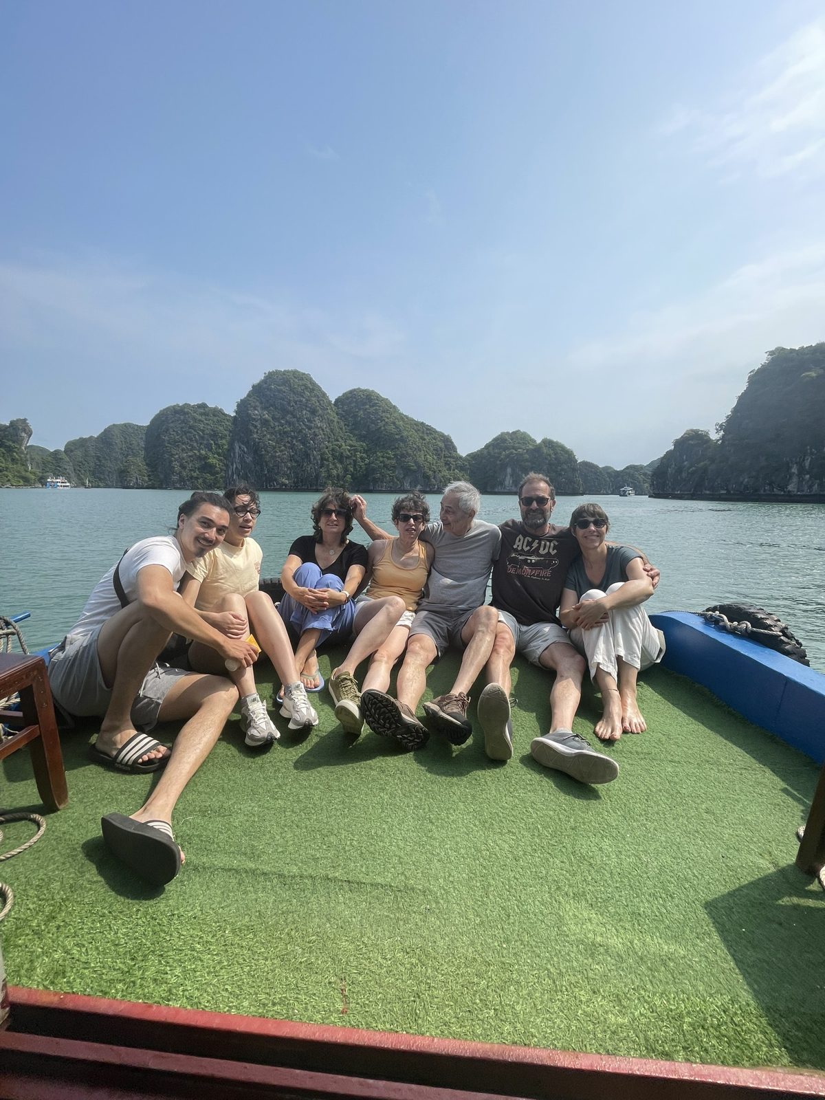 Family sitting on the wooden deck of a day boat crossing Lan Ha Bay