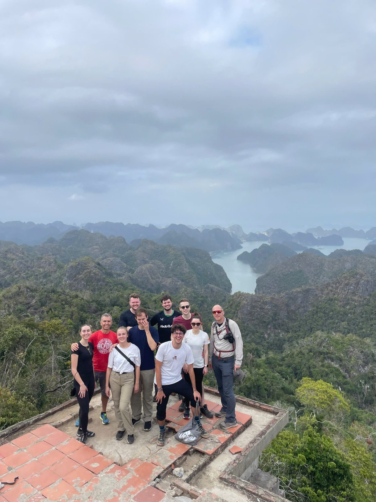 Group on the viewpoint steps above a misty Lan Ha Bay
