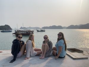 Group of travellers sitting on a pier looking over Lan Ha Bay