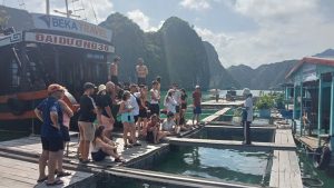 Group walking along a floating fishing village pontoon, Lan Ha Bay