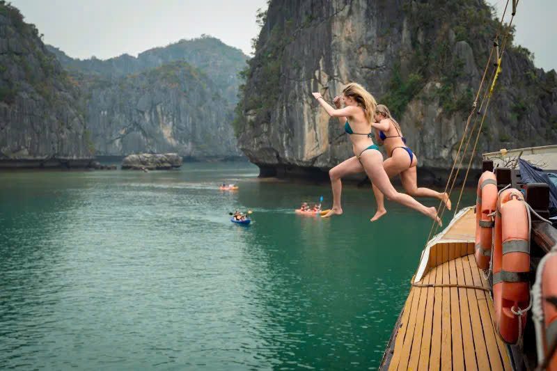 Traveller jumping off a boat into the water in Lan Ha Bay