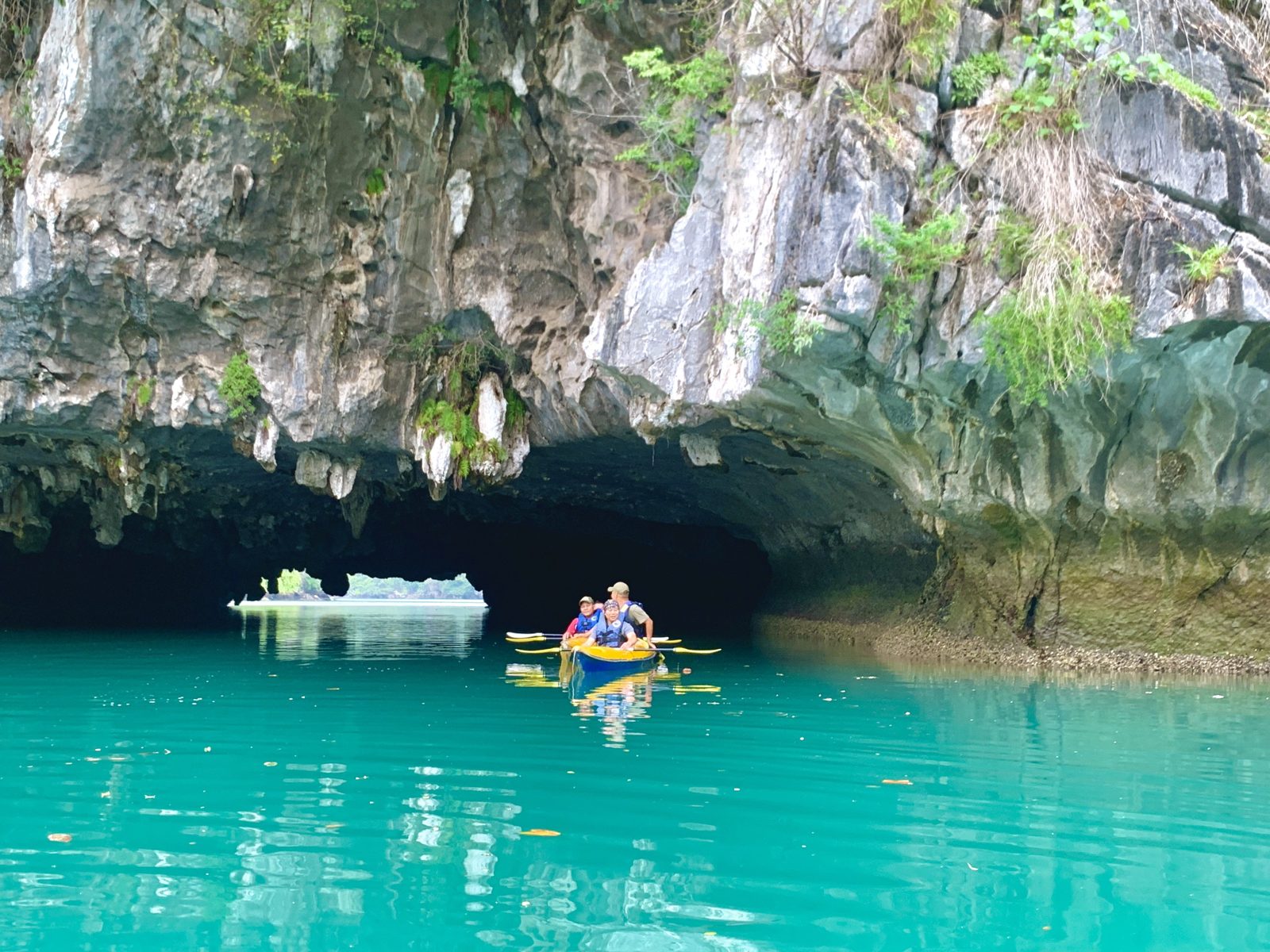 Kayak tunnel through limestone with turquoise water, Lan Ha Bay