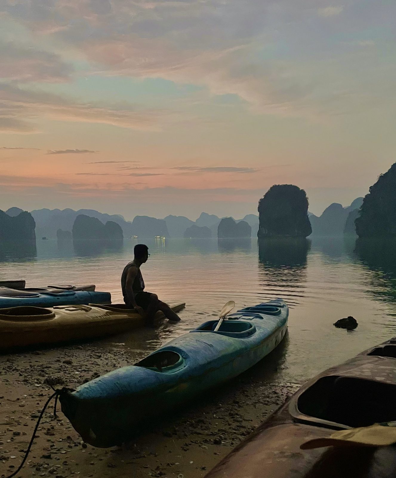 Kayaker sitting on the beach at sunrise in Lan Ha Bay