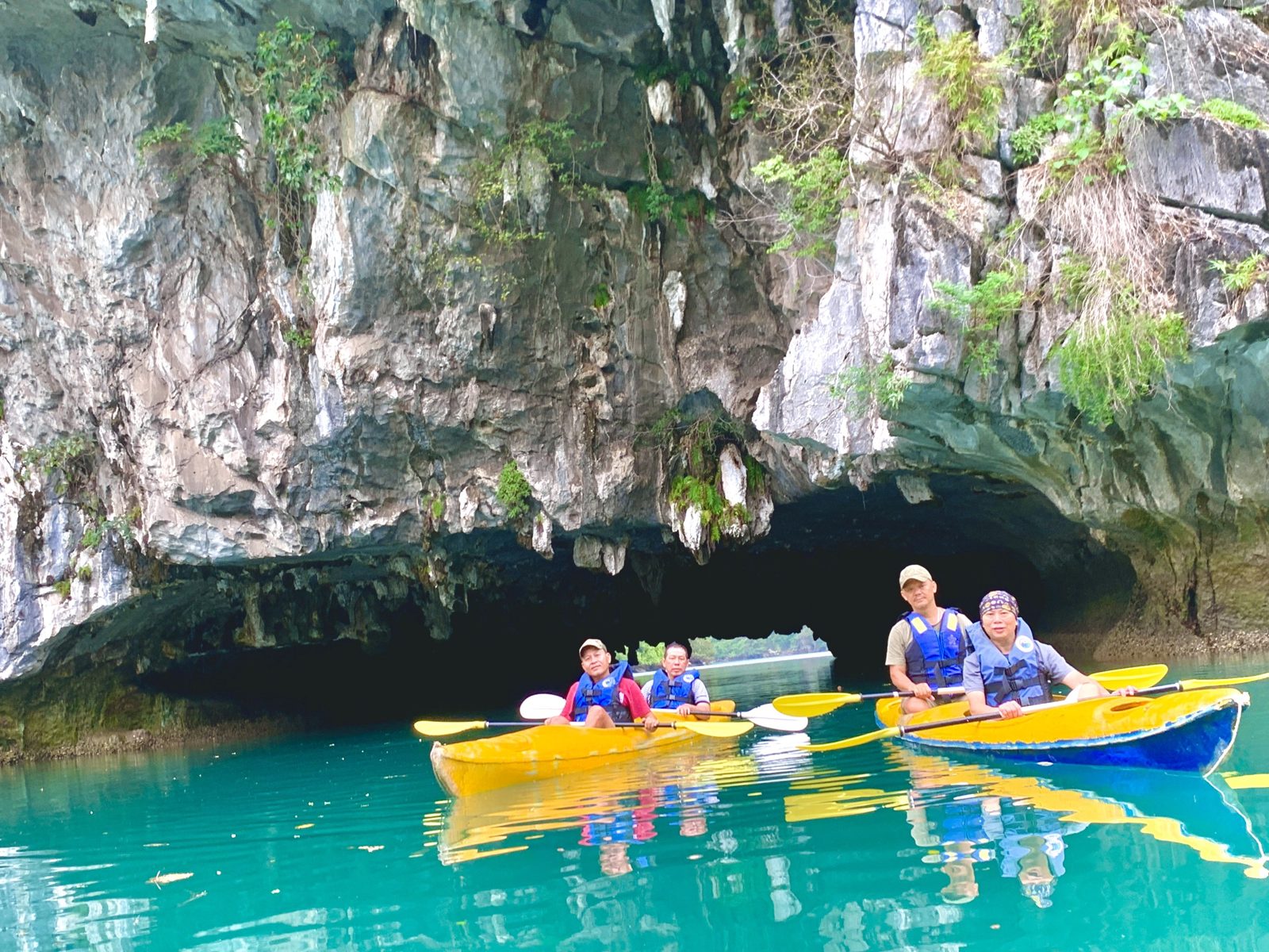 Group of kayaks gathered at the mouth of a sea cave, Lan Ha Bay