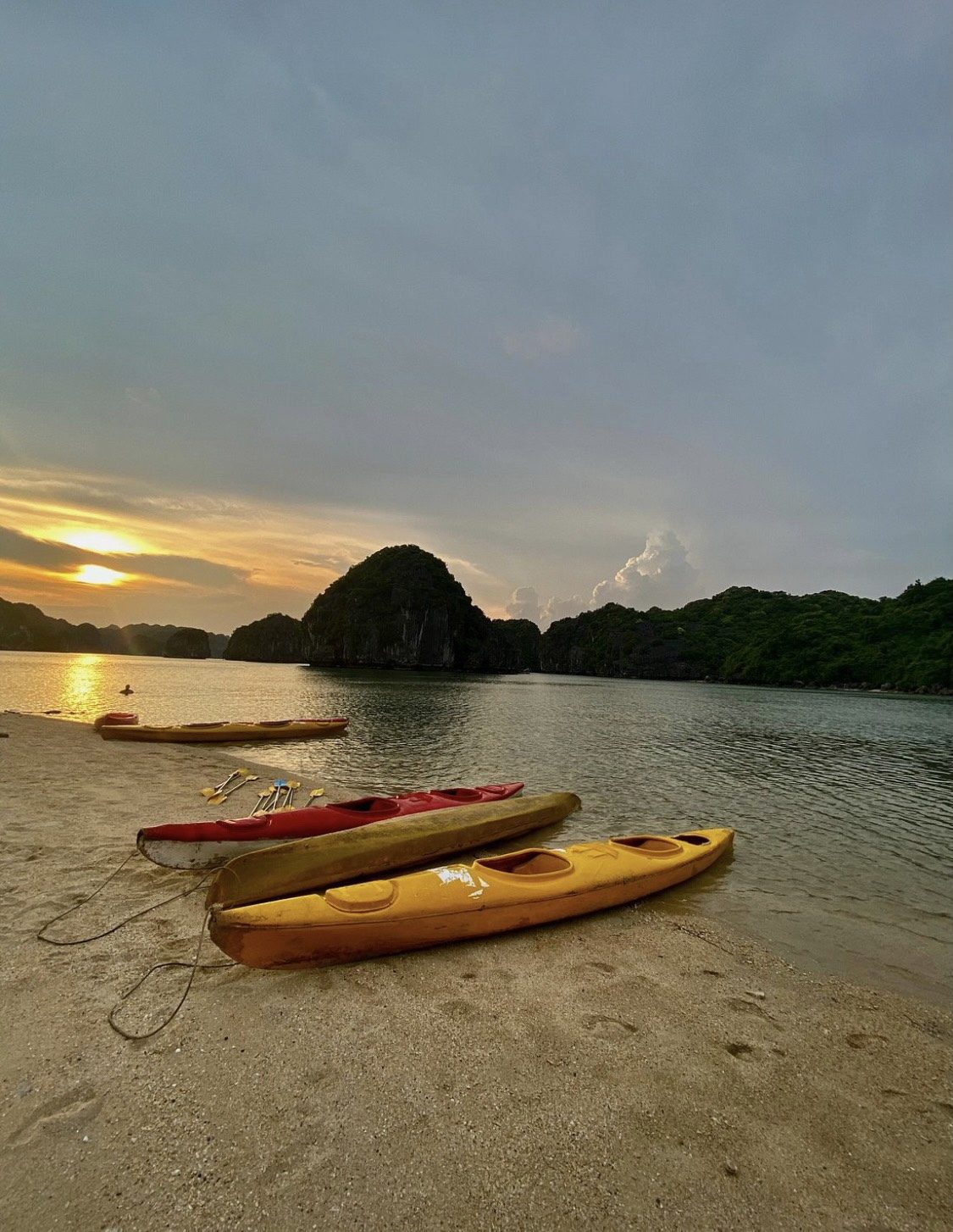 Kayaks pulled up on the sand at sunset in Lan Ha Bay