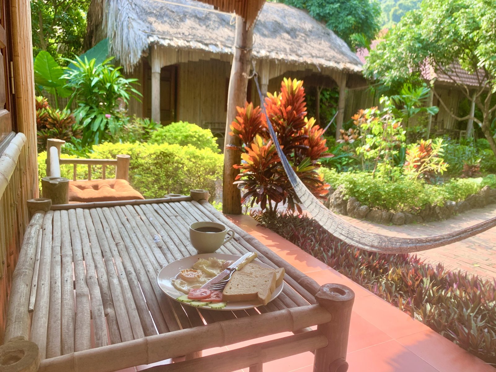 Wooden bungalow with a hammock and tropical garden at Lan Homestay, Viet Hai Village