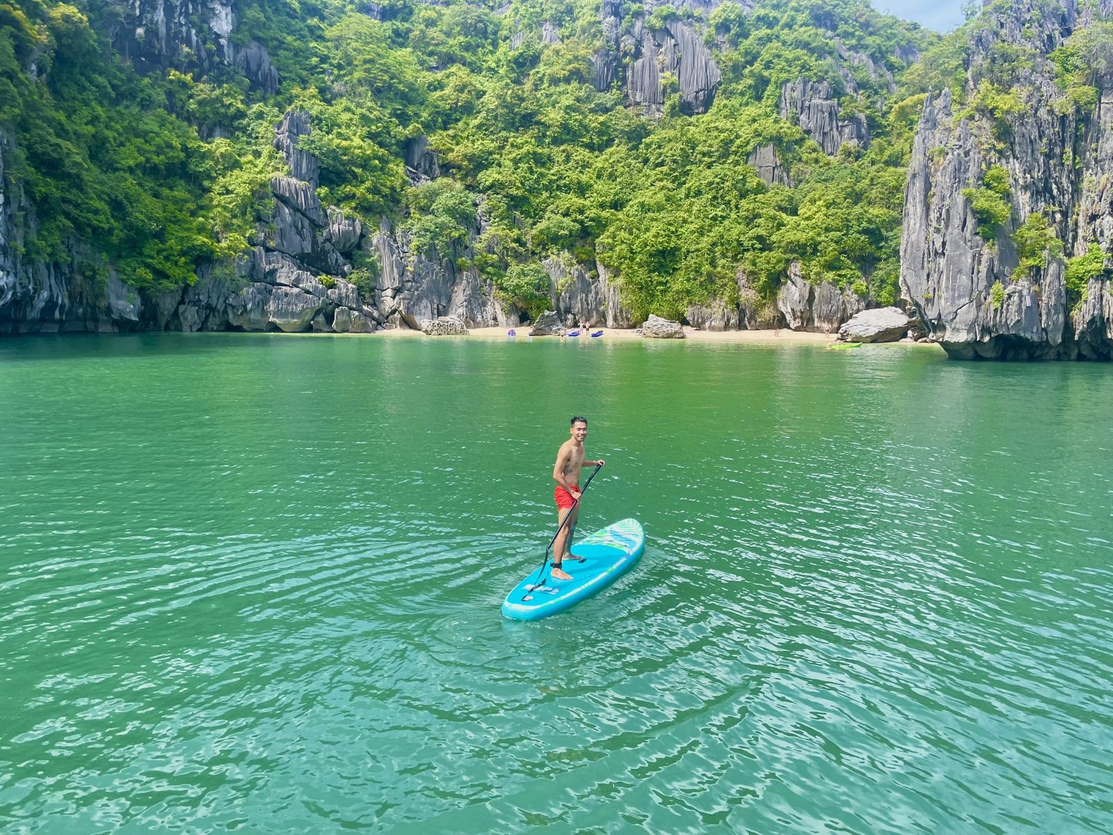 Paddleboarder crossing a limestone lagoon in Lan Ha Bay