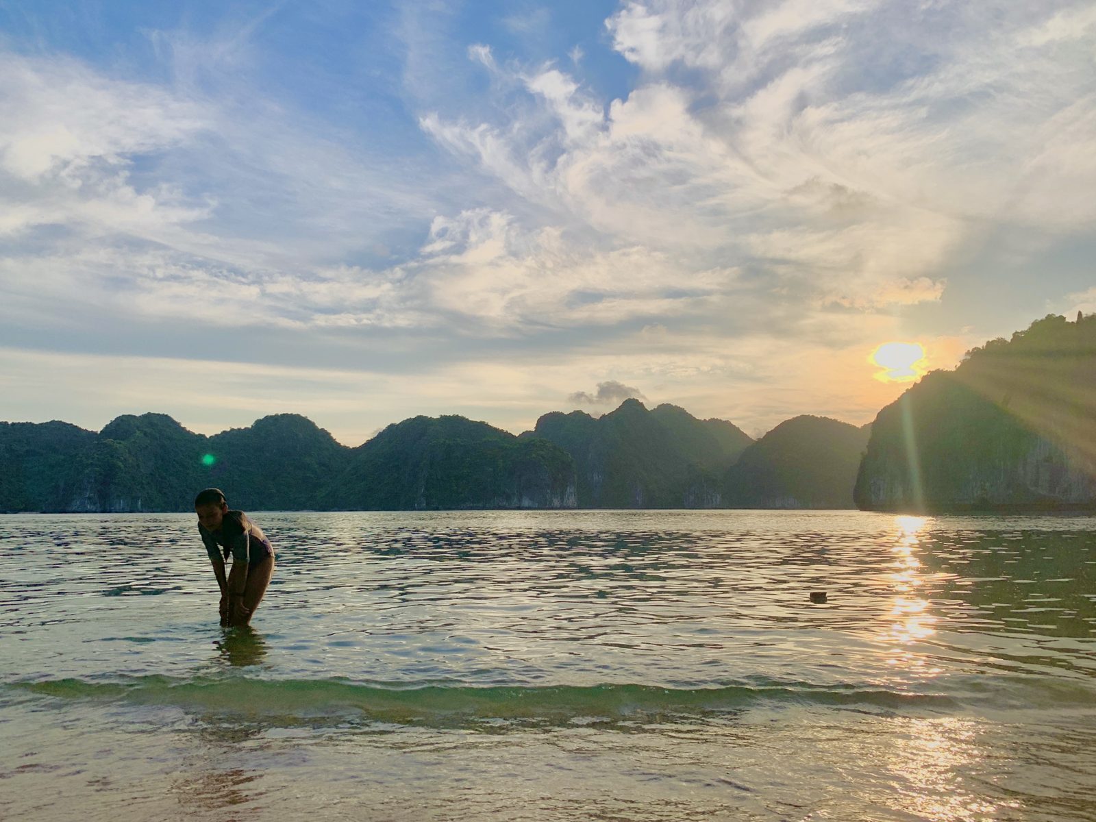 Swimmer silhouetted against the sunset in Lan Ha Bay