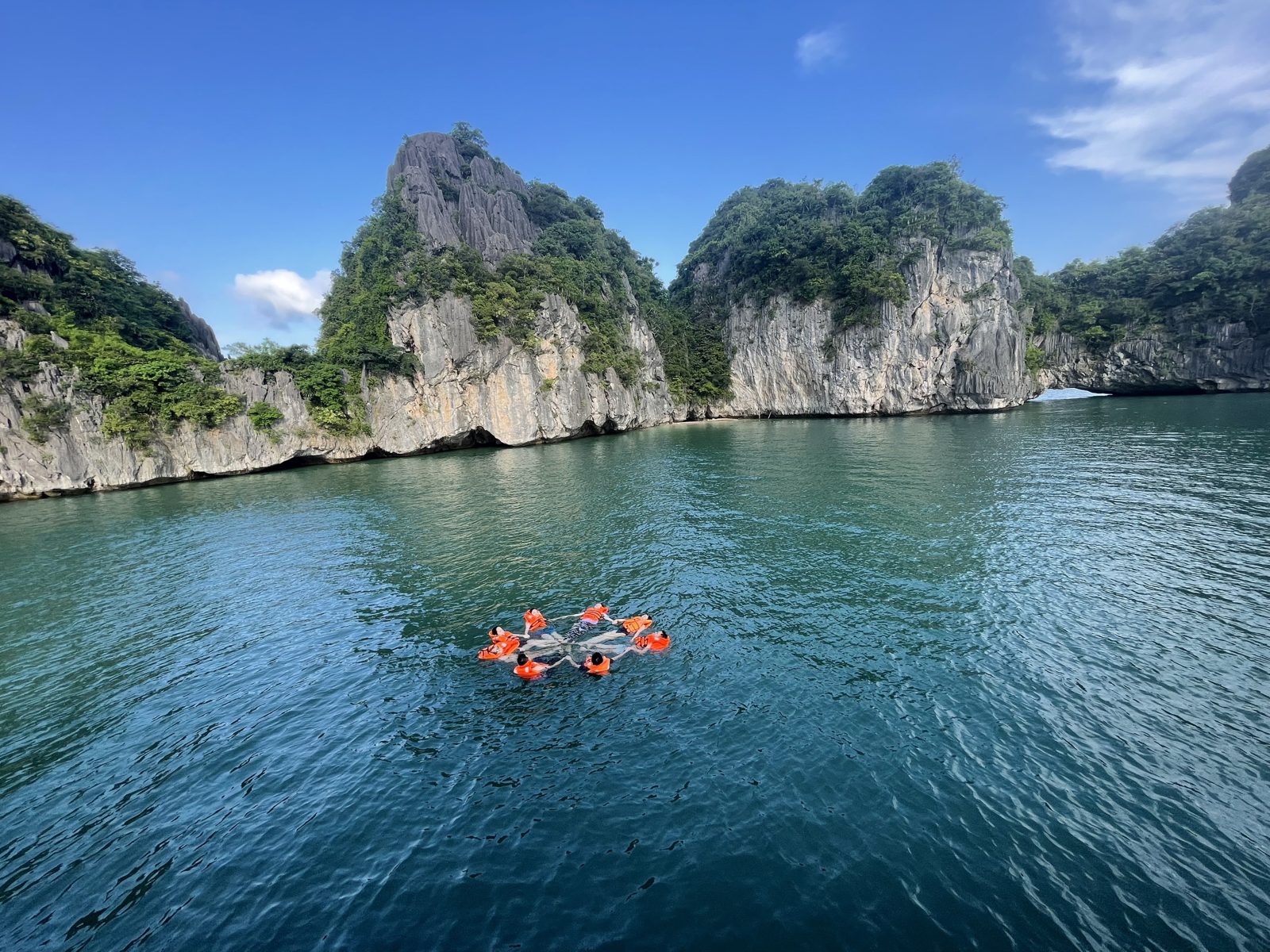 Group swimming in life jackets between limestone karsts in Lan Ha Bay