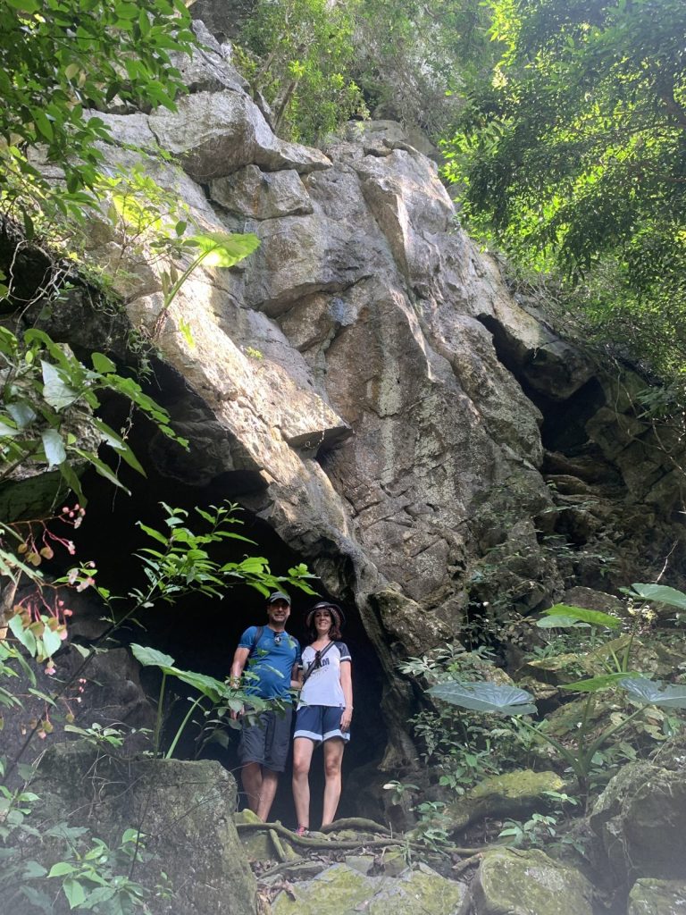 Travellers standing at a cave mouth in the Cat Ba jungle