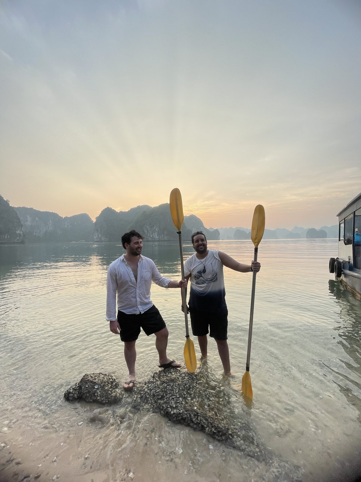 Two paddlers holding kayak paddles at sunrise on Lan Ha Bay