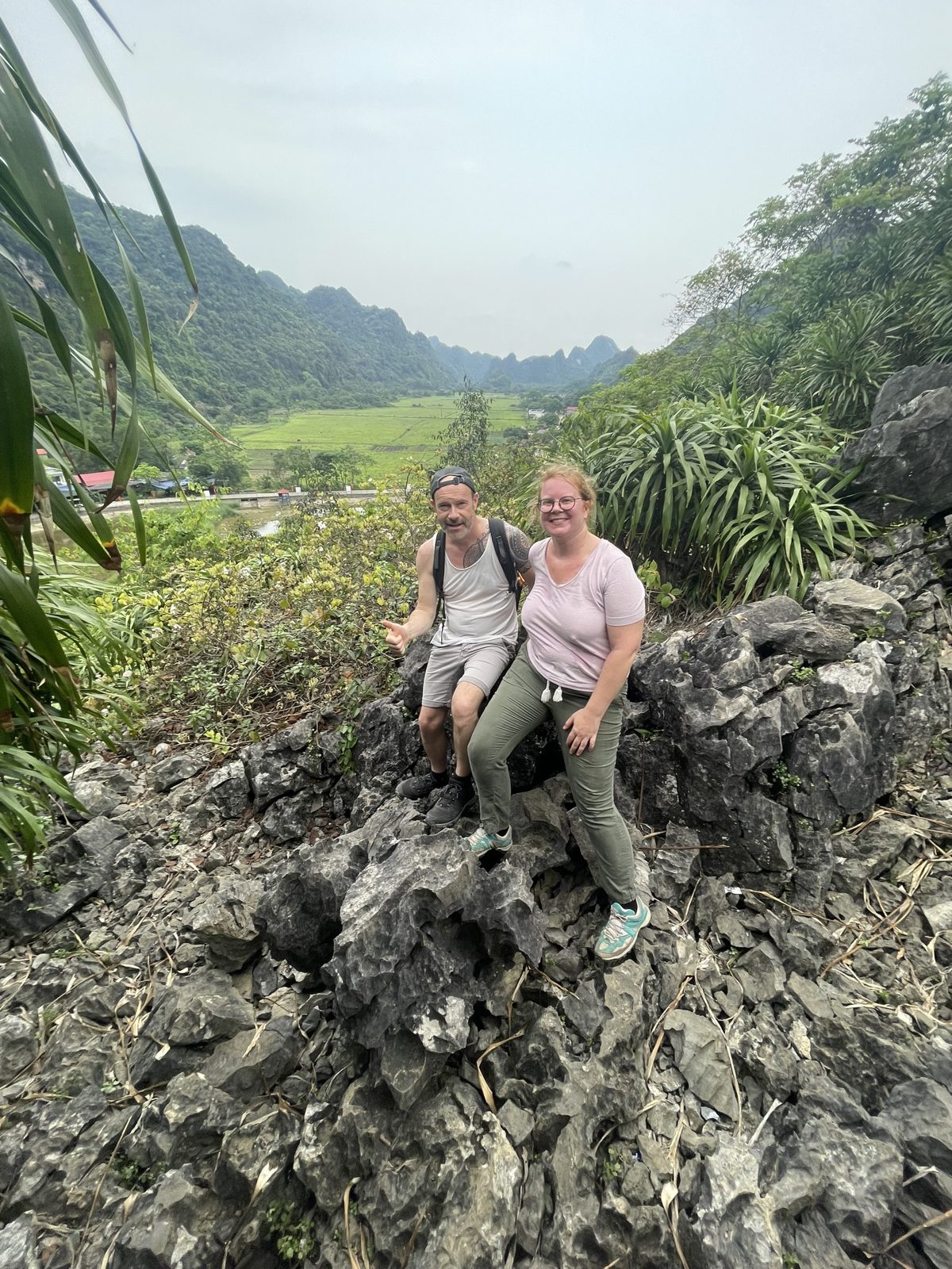 Two travellers sitting on limestone rocks in the Viet Hai valley, Cat Ba Island