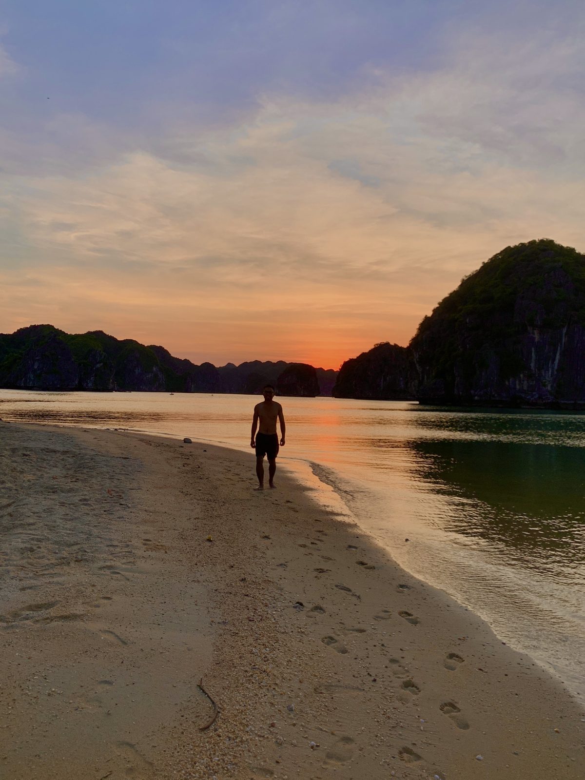 Person walking alone along a beach at sunset, Cat Ba Island